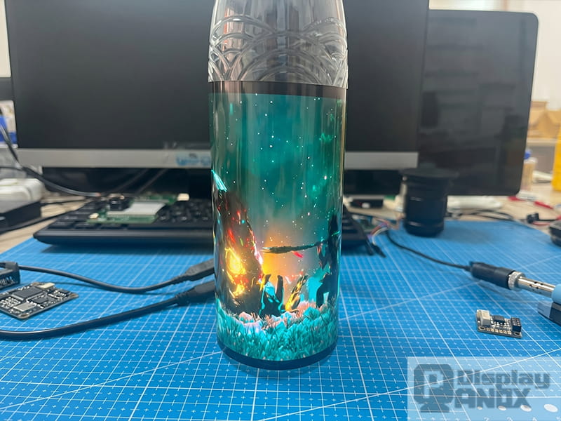 Flexible OLED display curled around water bottle demonstrating thin film flexibility and active display