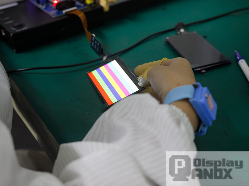 Phone screen quality inspection showing color bar test during display panel production